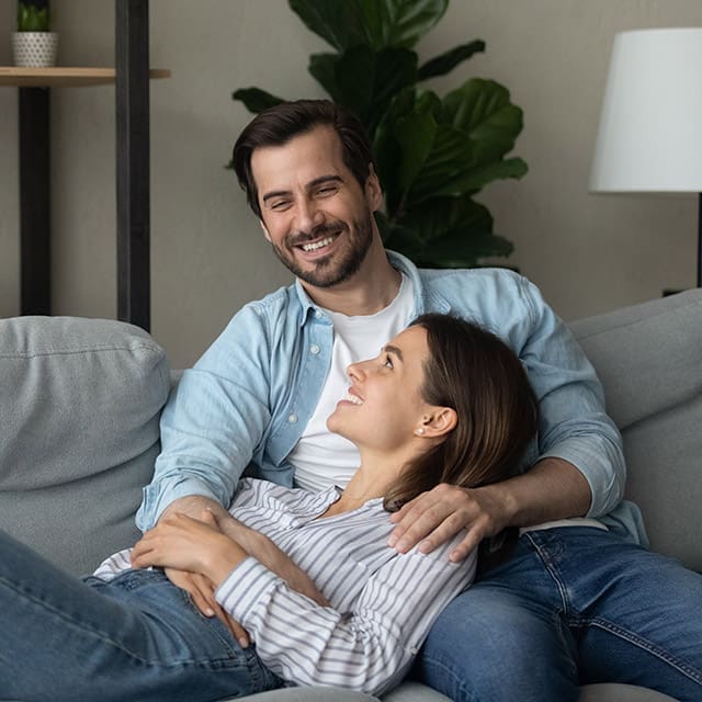 Young Couple laughing on couch in new home