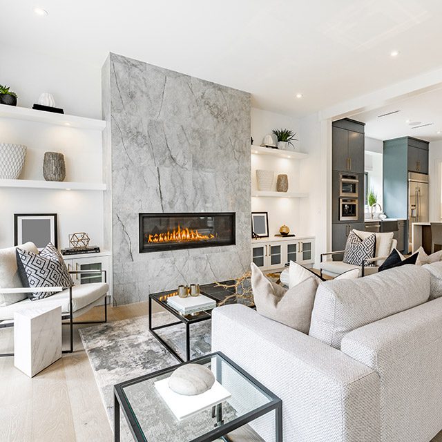 contemporary living room with open concept view through to dining room kitchen and a marble fireplace with gas fire