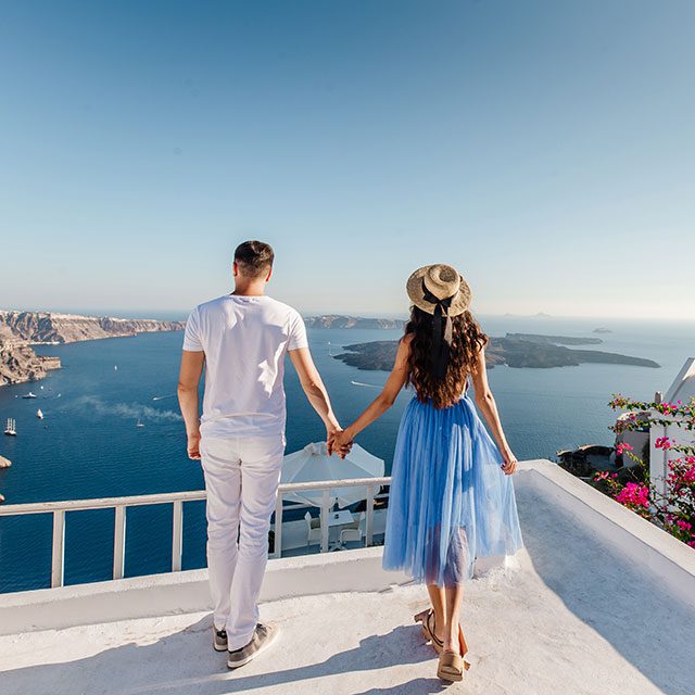 Young couple holding hands and enjoying view on Santorini Island, Greece