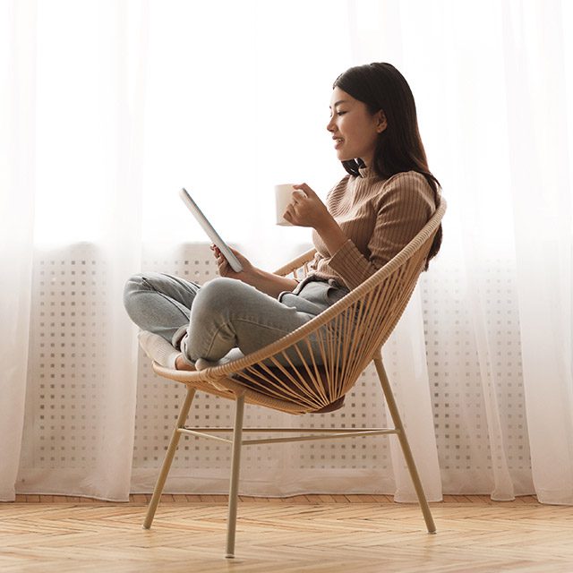 Young woman in cane chair reading property advice