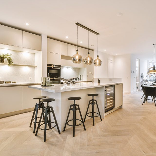 Home interior design of modern loft apartment with open kitchen in minimalist style and spacious dining zone with table and chairs